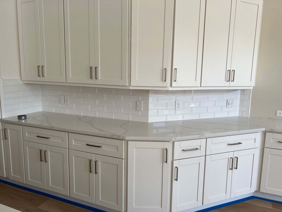 White shaker kitchen with a white subway tile backsplash under quartz counters