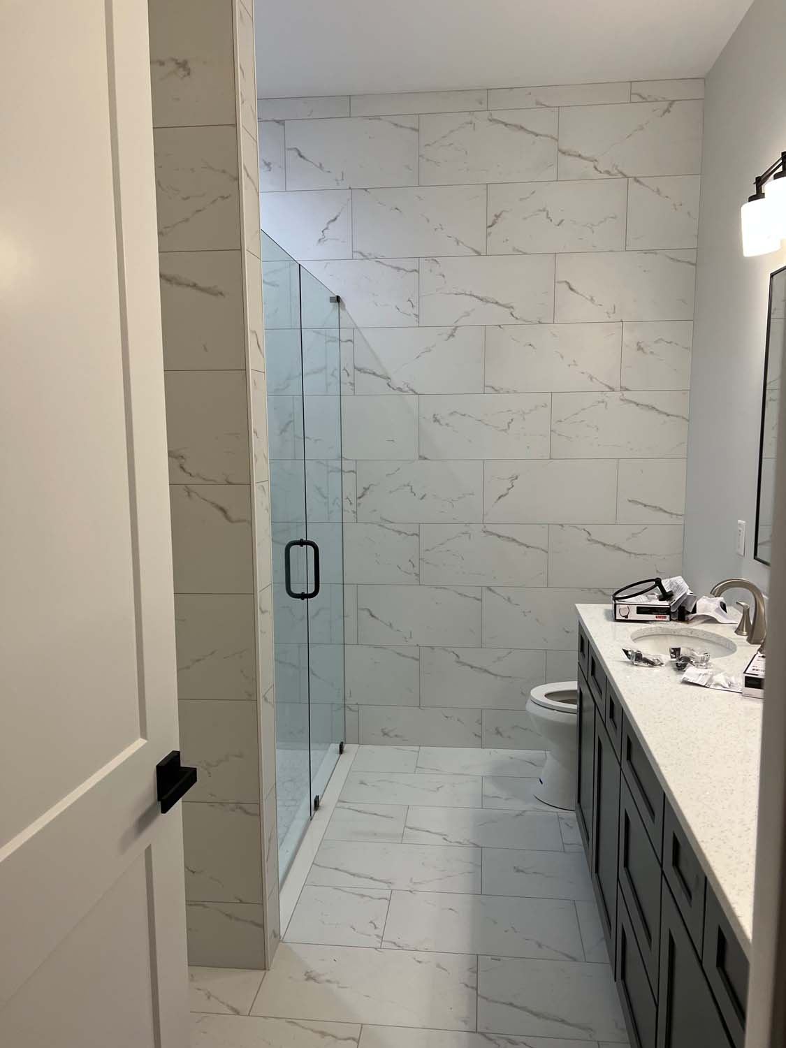 Large-format marble-look porcelain shower with a frameless glass door