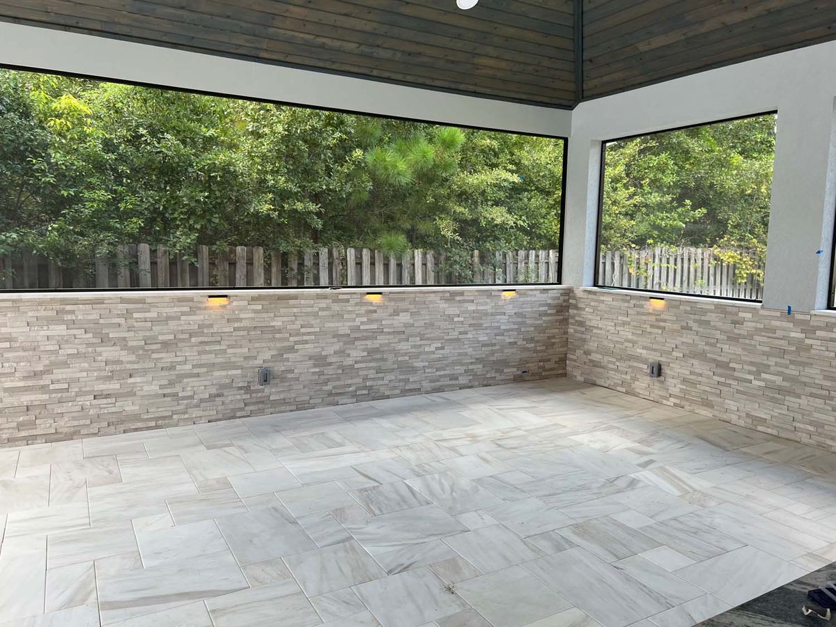 Screened lanai with a large-format porcelain floor and a stacked stone knee wall