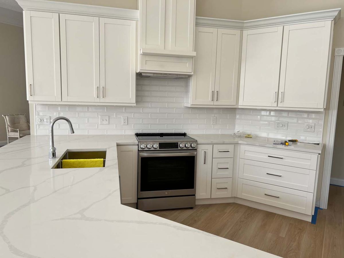 White subway tile backsplash in an L-shaped kitchen with quartz counters