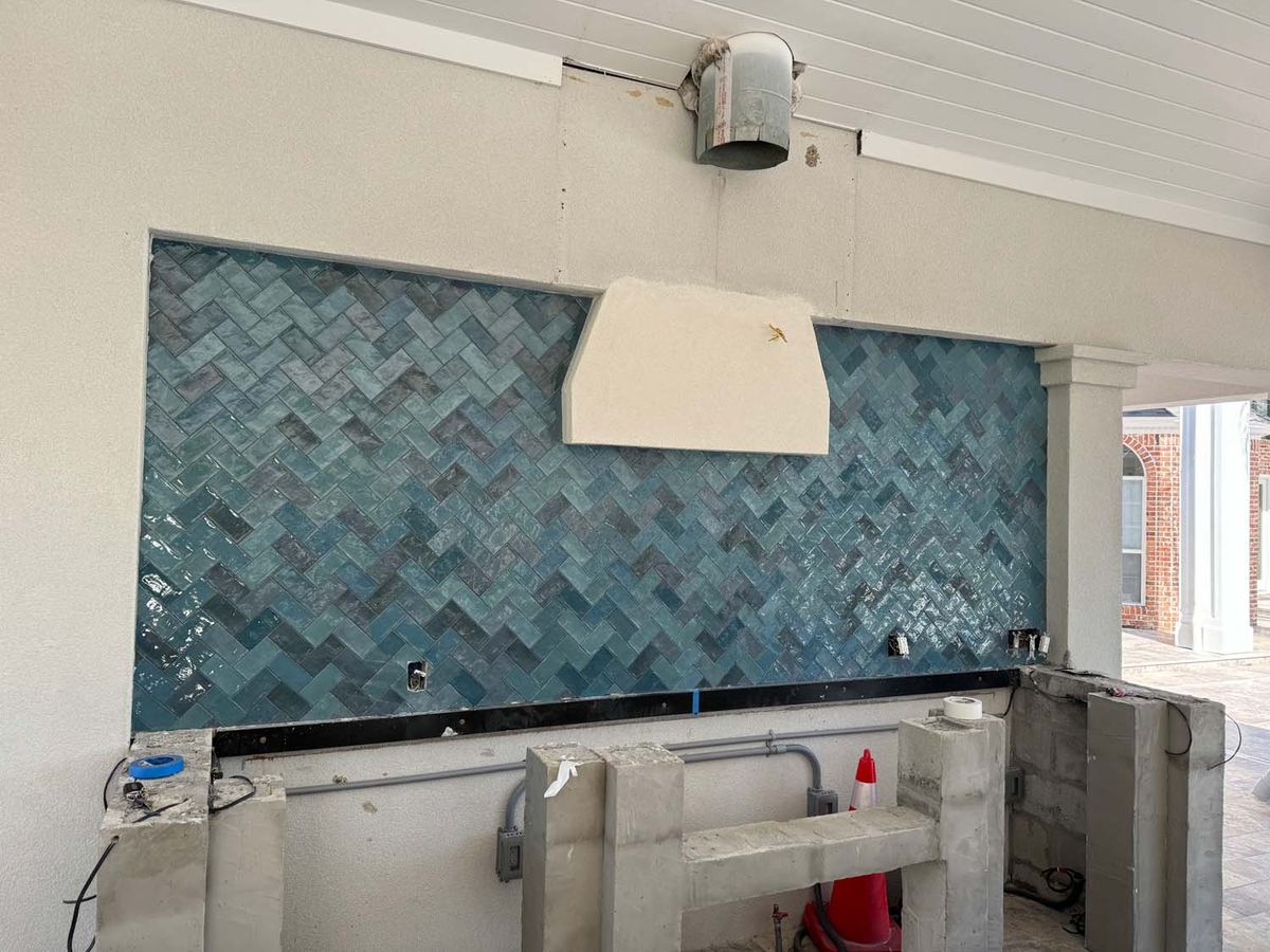 Blue glazed herringbone backsplash going up on an outdoor kitchen wall