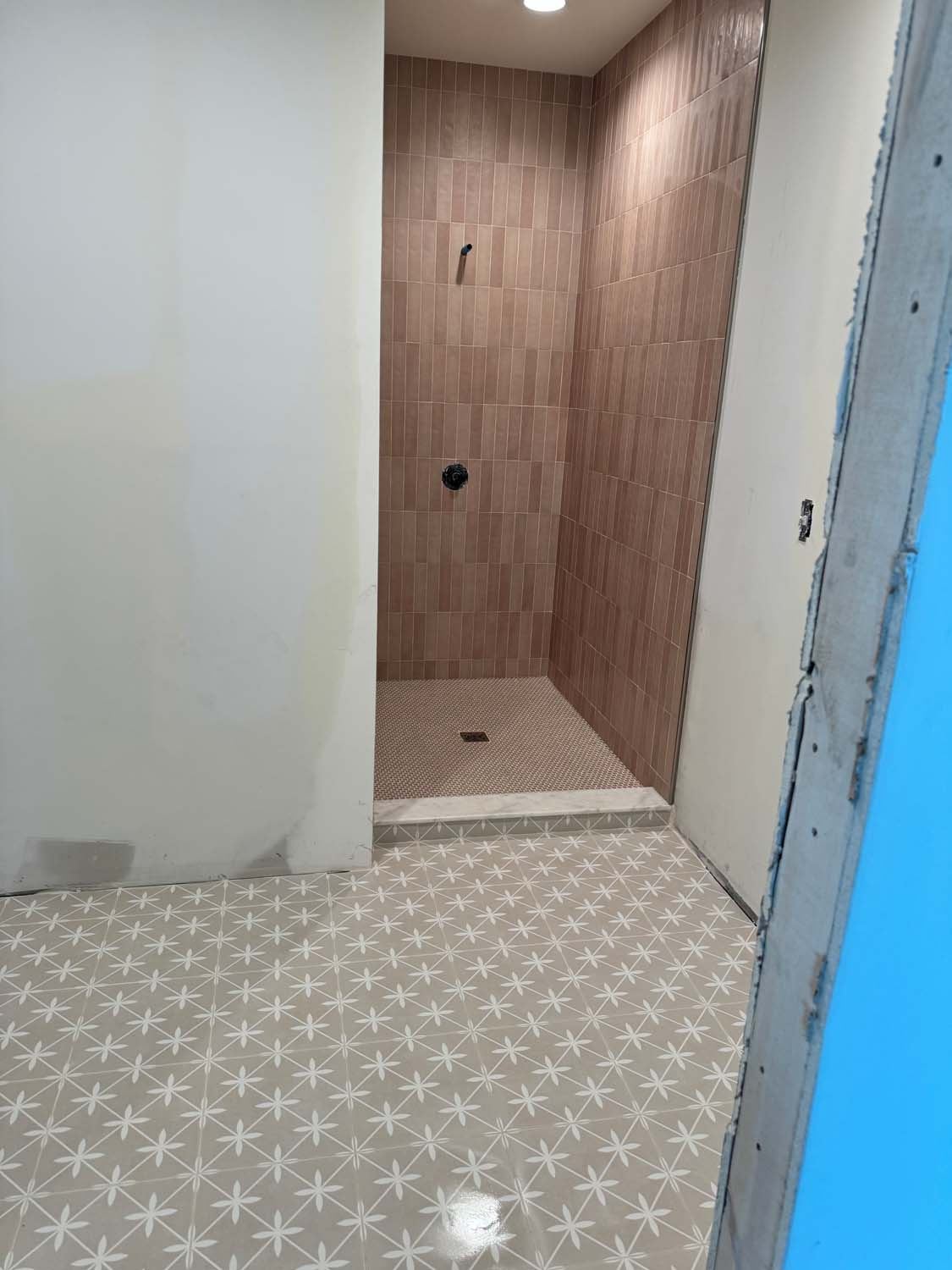 Wood-look plank tile shower with a patterned porcelain bathroom floor