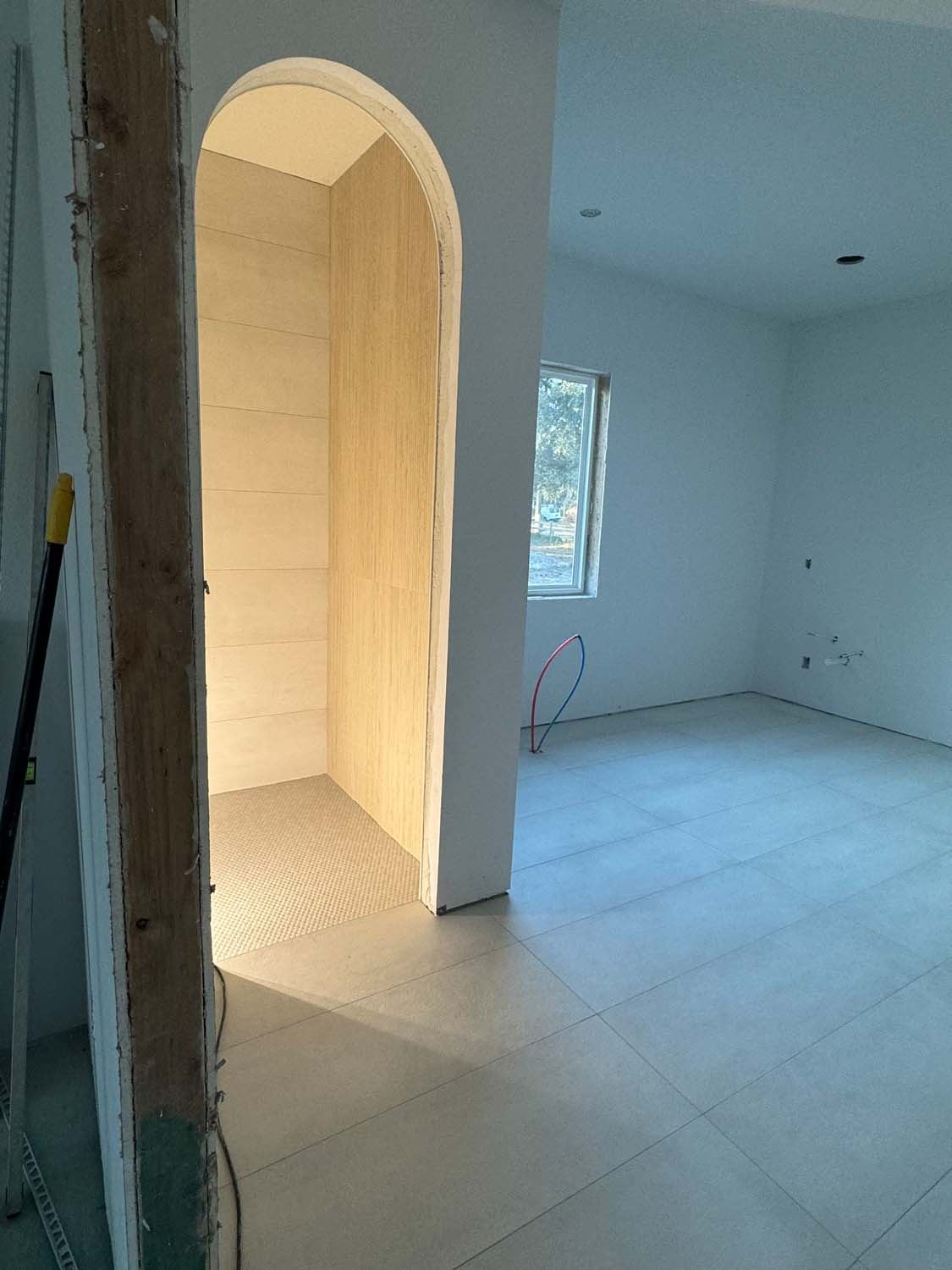 Arched shower entry in large-format tile in a bathroom under construction