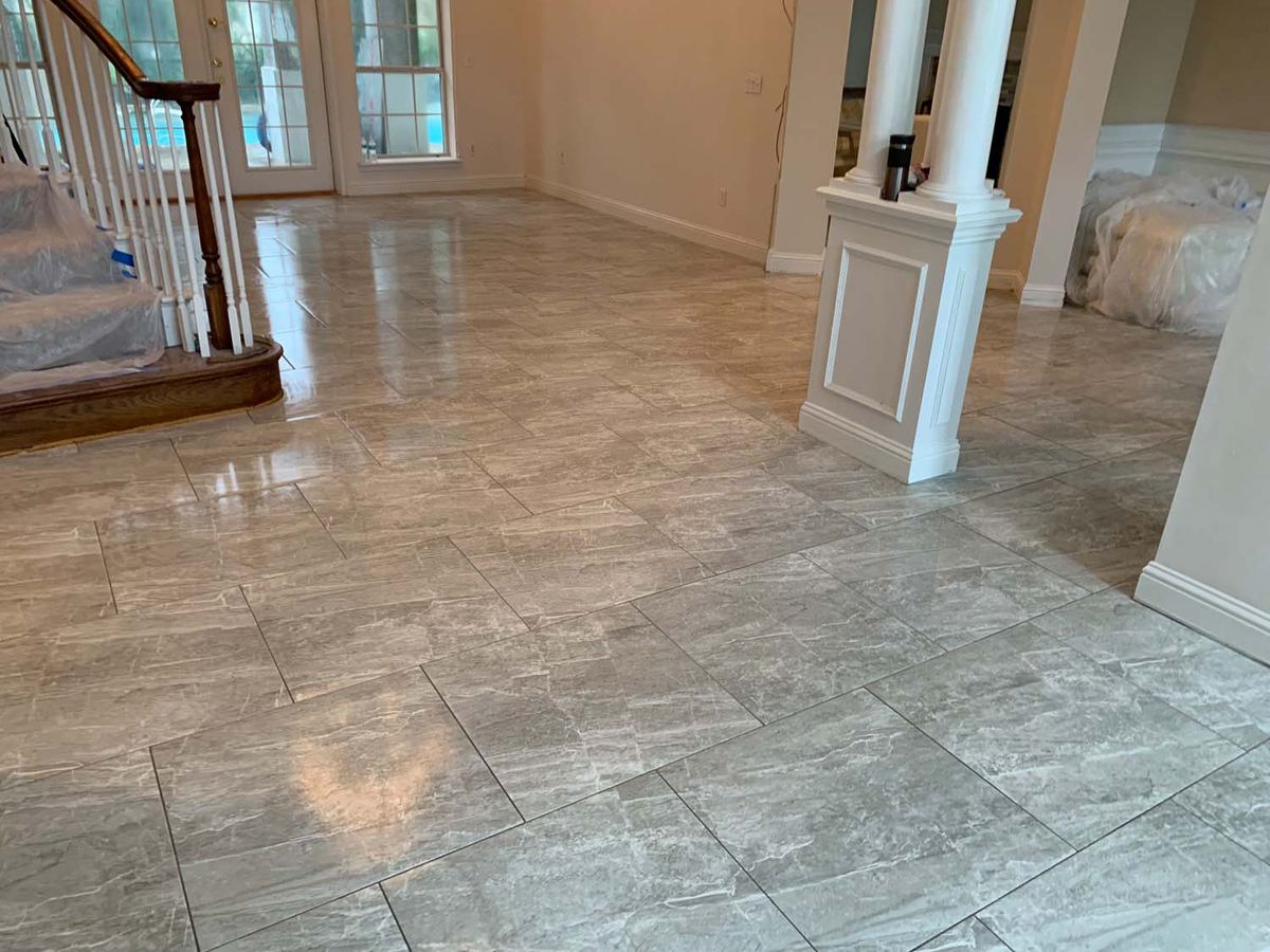 Large-format porcelain floor through a living room and stair landing