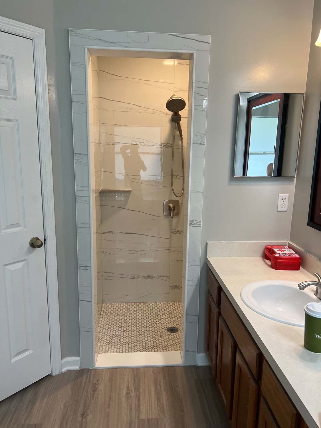 Walk-in shower with a tiled niche, seen past the vanity