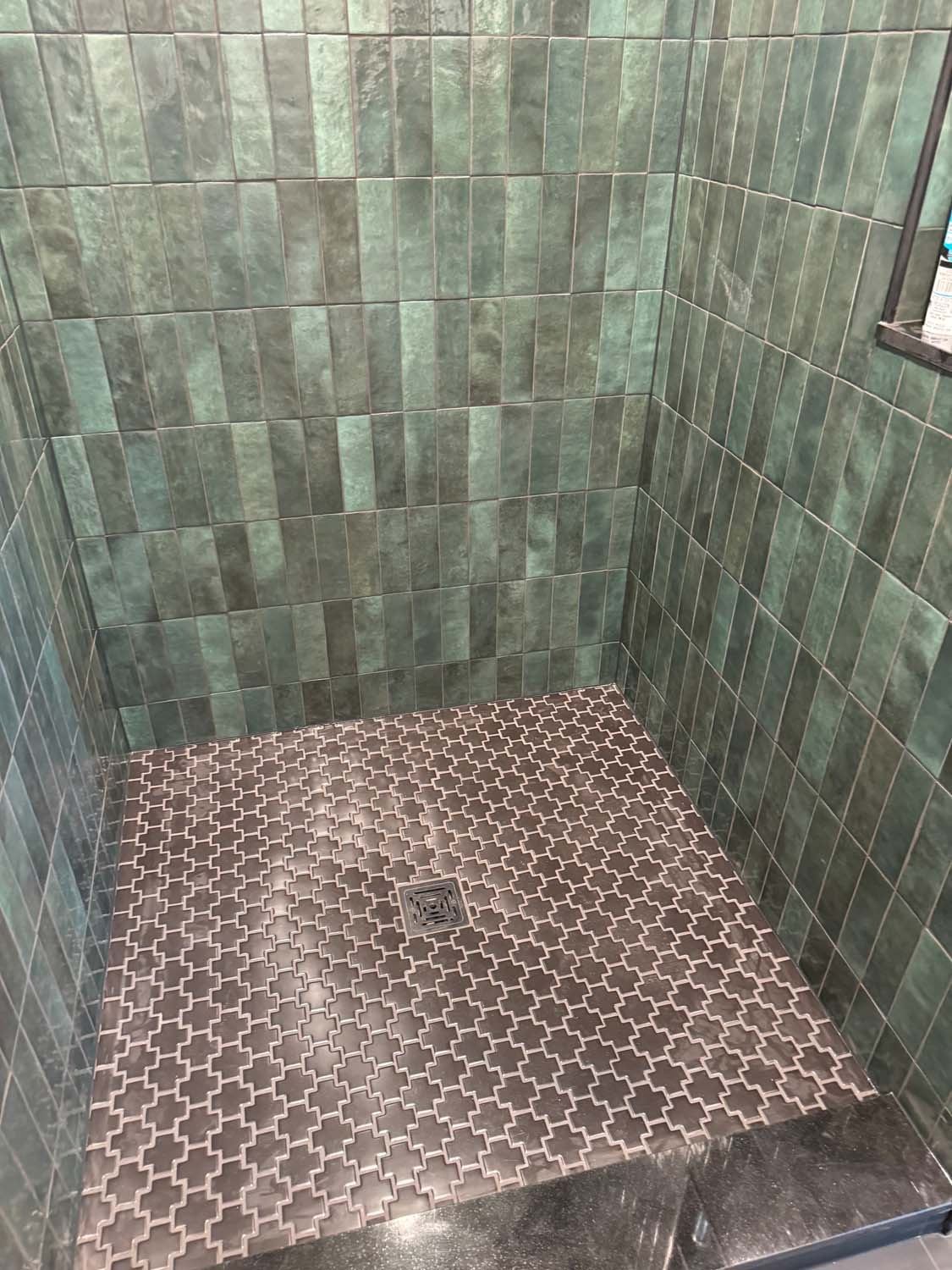 Green glazed tile shower with an arabesque mosaic floor