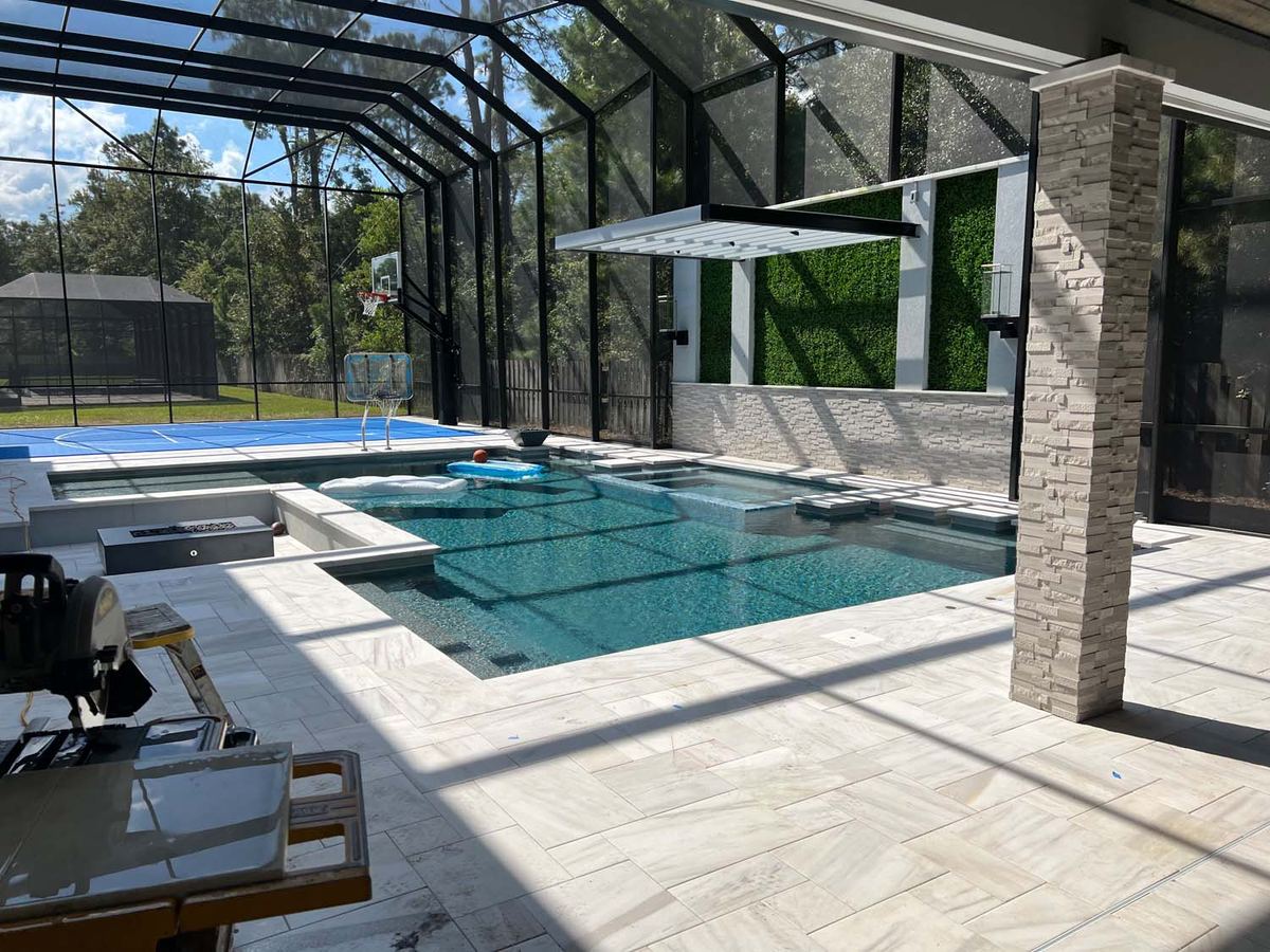 Screened pool with a travertine-look deck and a stacked stone column