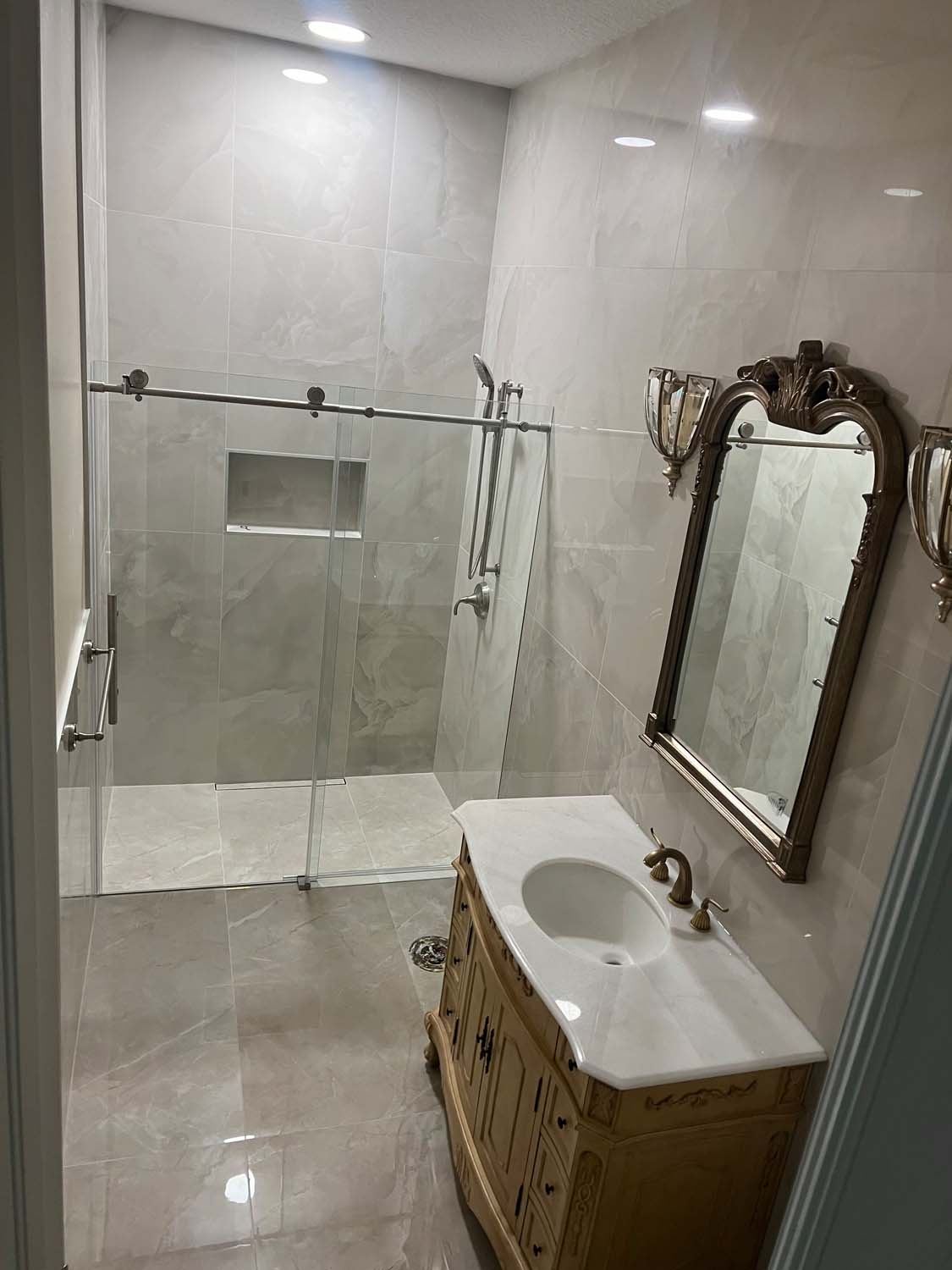 Marble-look shower behind glass beside an antique vanity