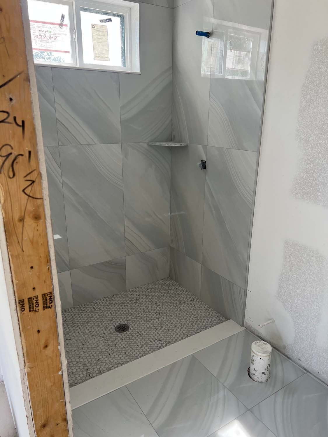 Gray porcelain shower with a pebble floor