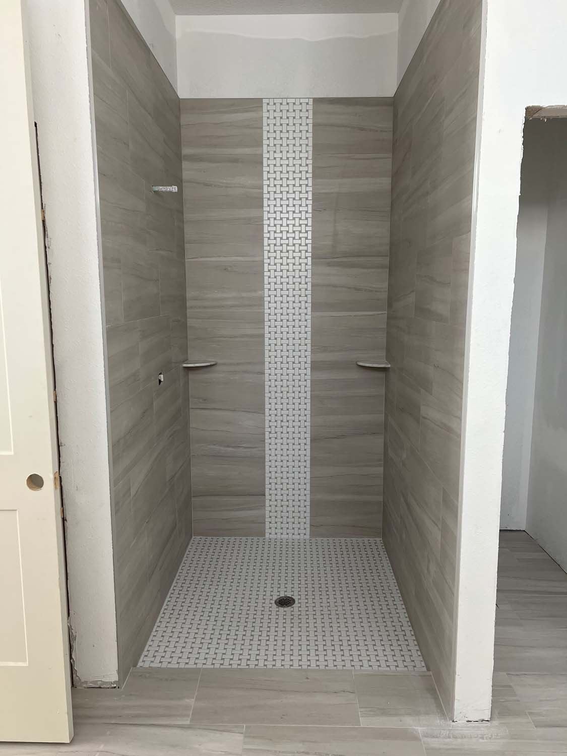 Gray plank tile shower with a white mosaic stripe
