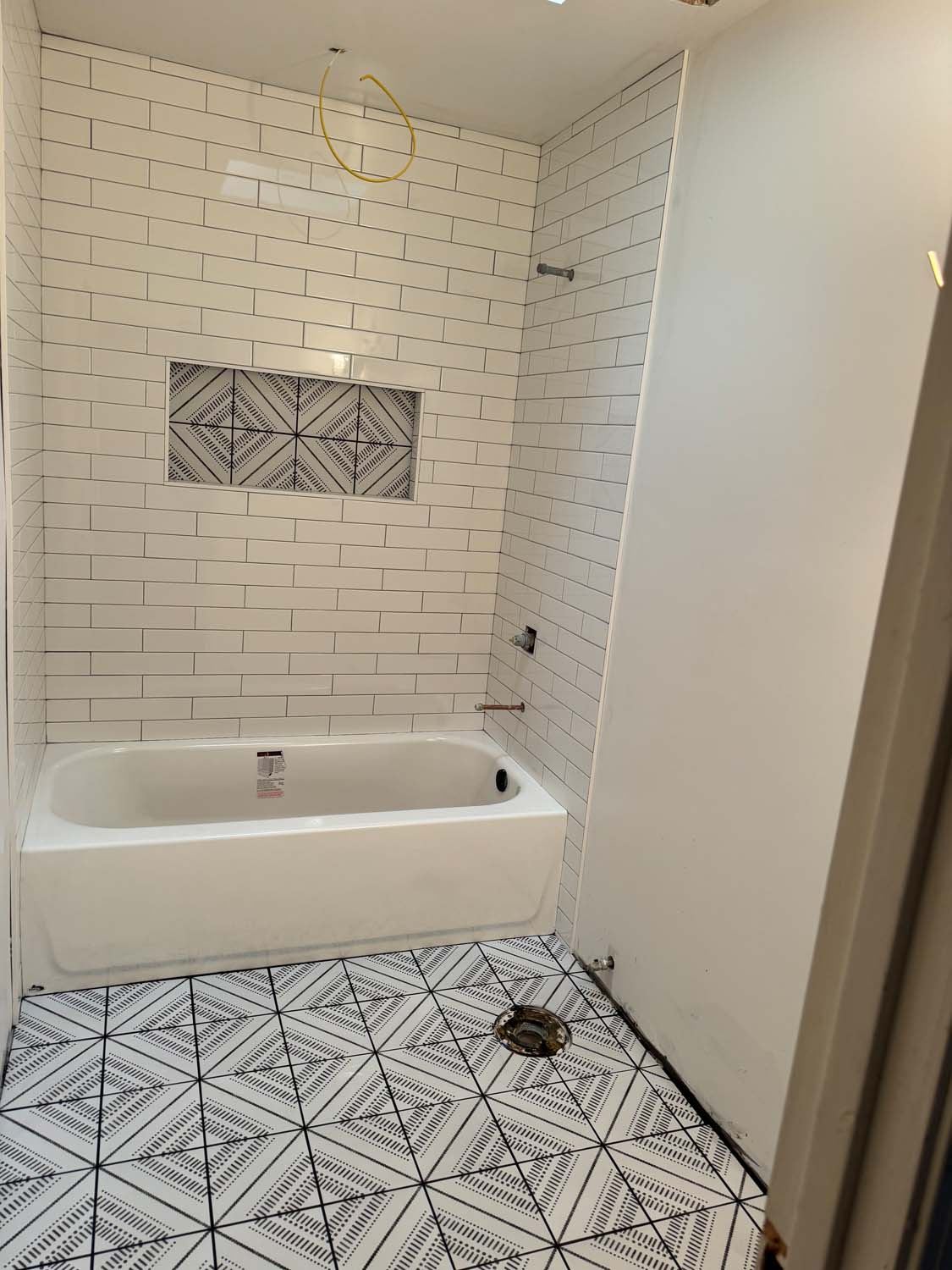 Subway tile tub surround with a decorative niche and a patterned floor