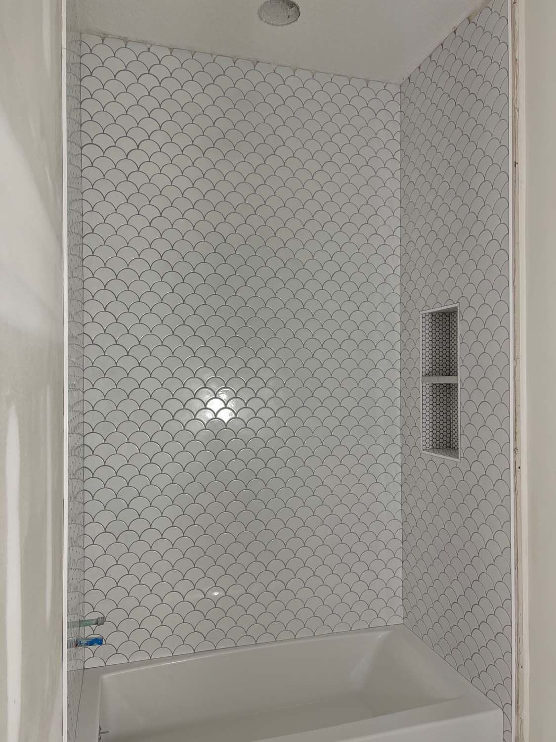 White arabesque tile shower with twin niches