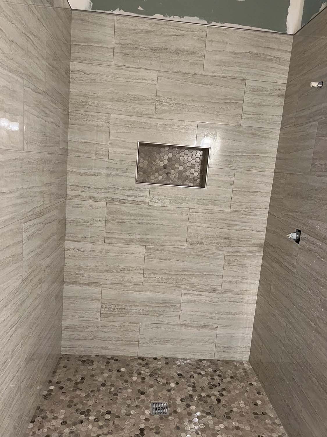 Wood-look shower with a mosaic niche and a pebble floor