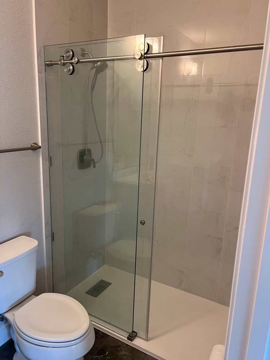Shower with a sliding glass door and large-format tile