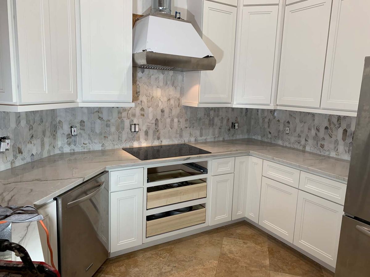 Kitchen with a stone mosaic backsplash behind the range hood