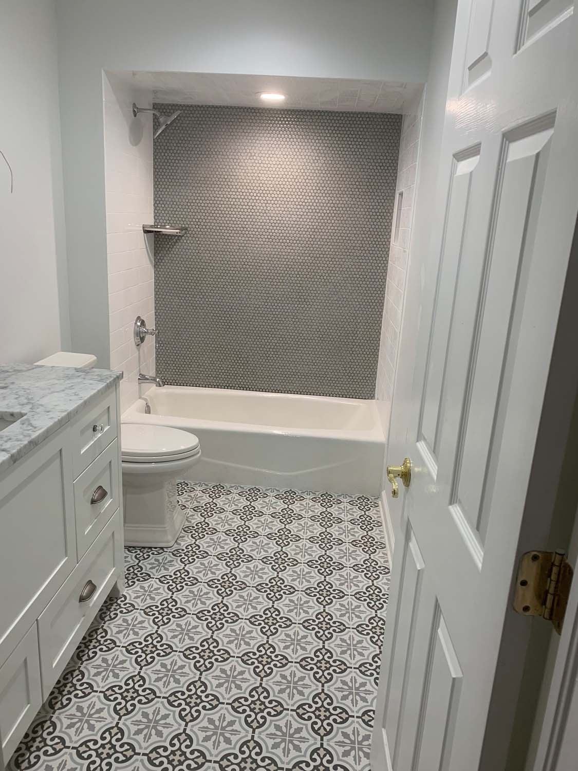 Gray tile tub surround over a patterned cement-look floor