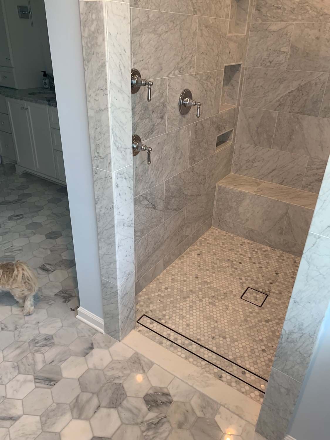 Walk-in marble-look shower with a linear drain and a hexagon floor