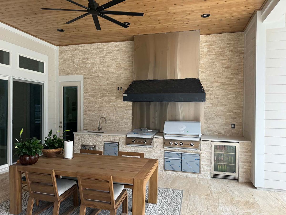 Outdoor kitchen with a stacked stone wall and a porcelain floor under a wood ceiling