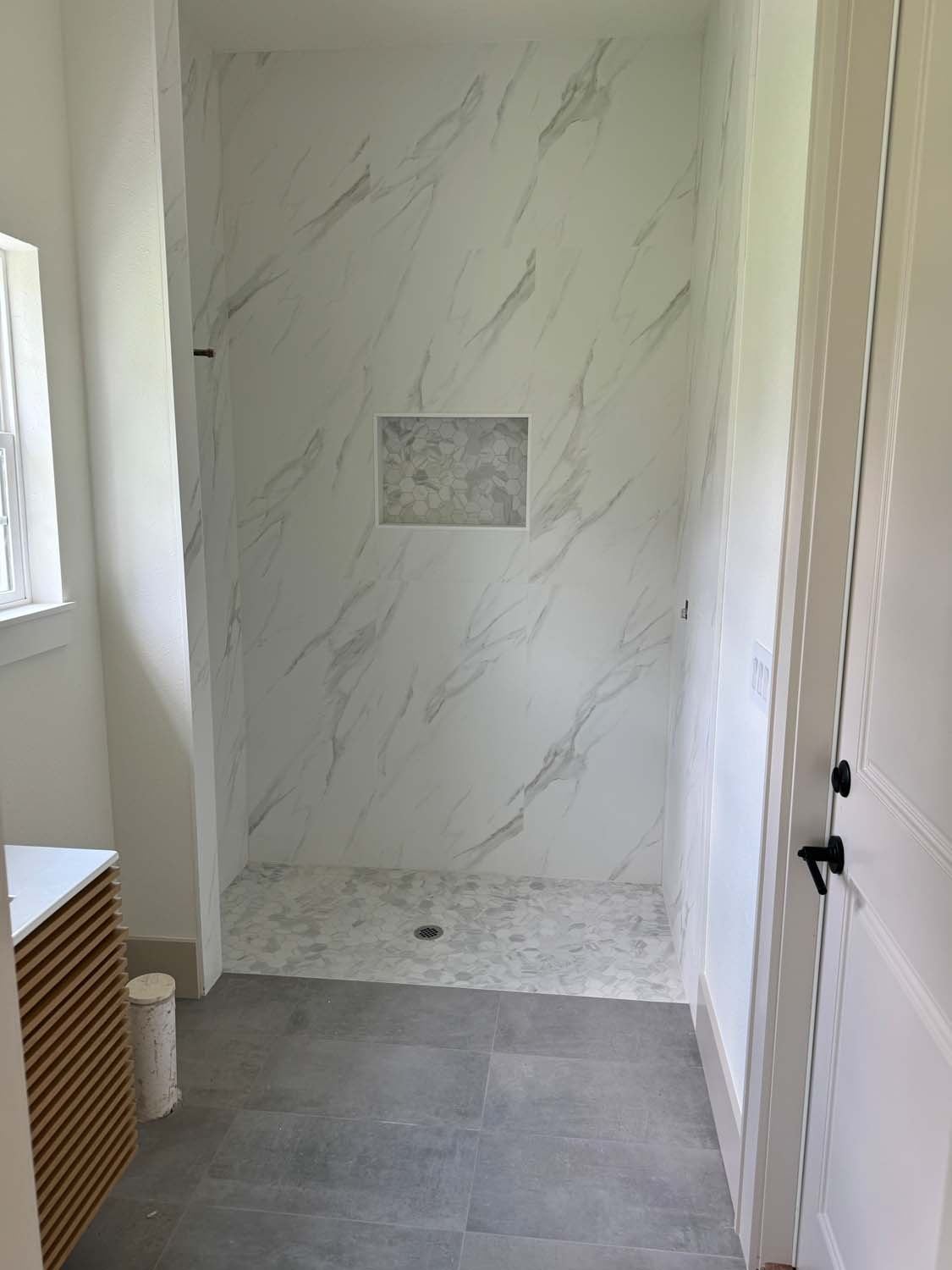 Marble-look shower with a niche and a mosaic floor