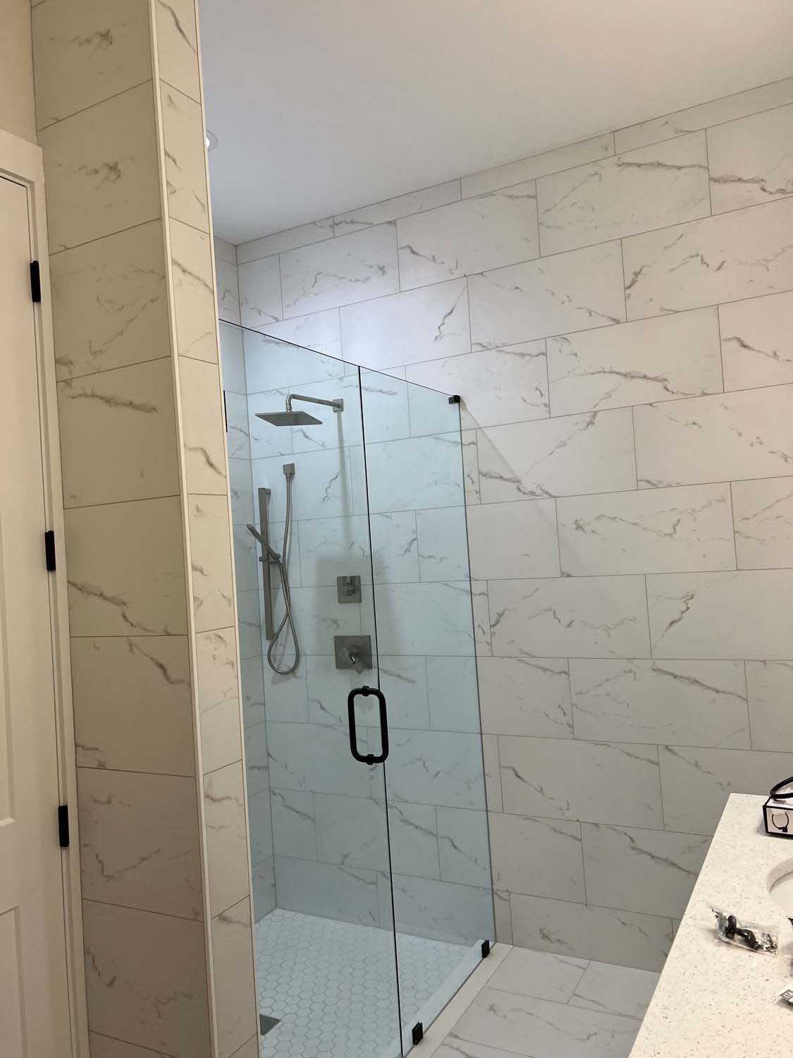 Marble-look shower with frameless glass and a rain head