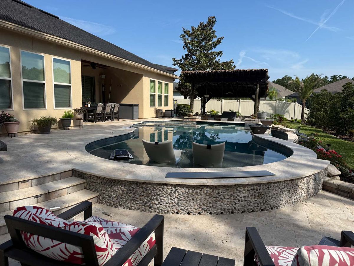 Raised spa in pebble mosaic on a travertine pool deck