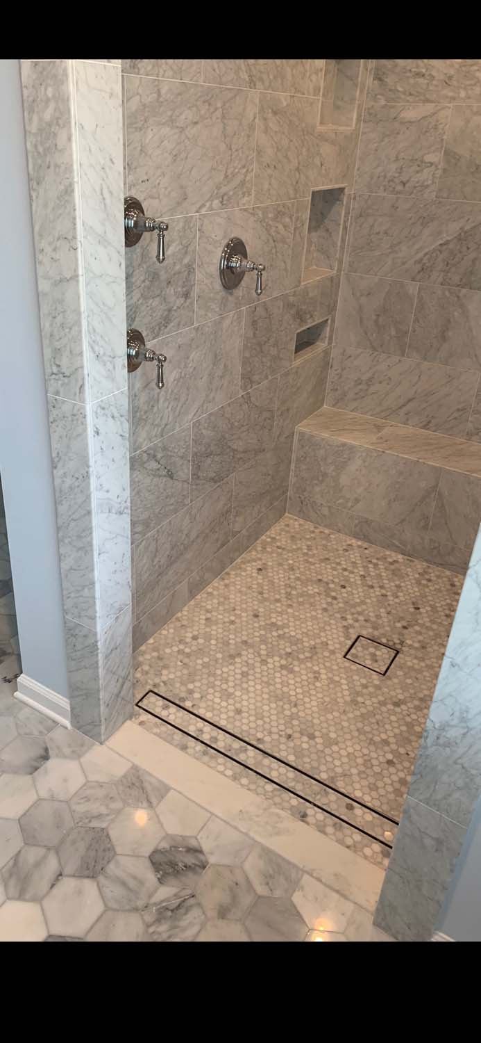 Marble-look shower with a hexagon floor and a bench