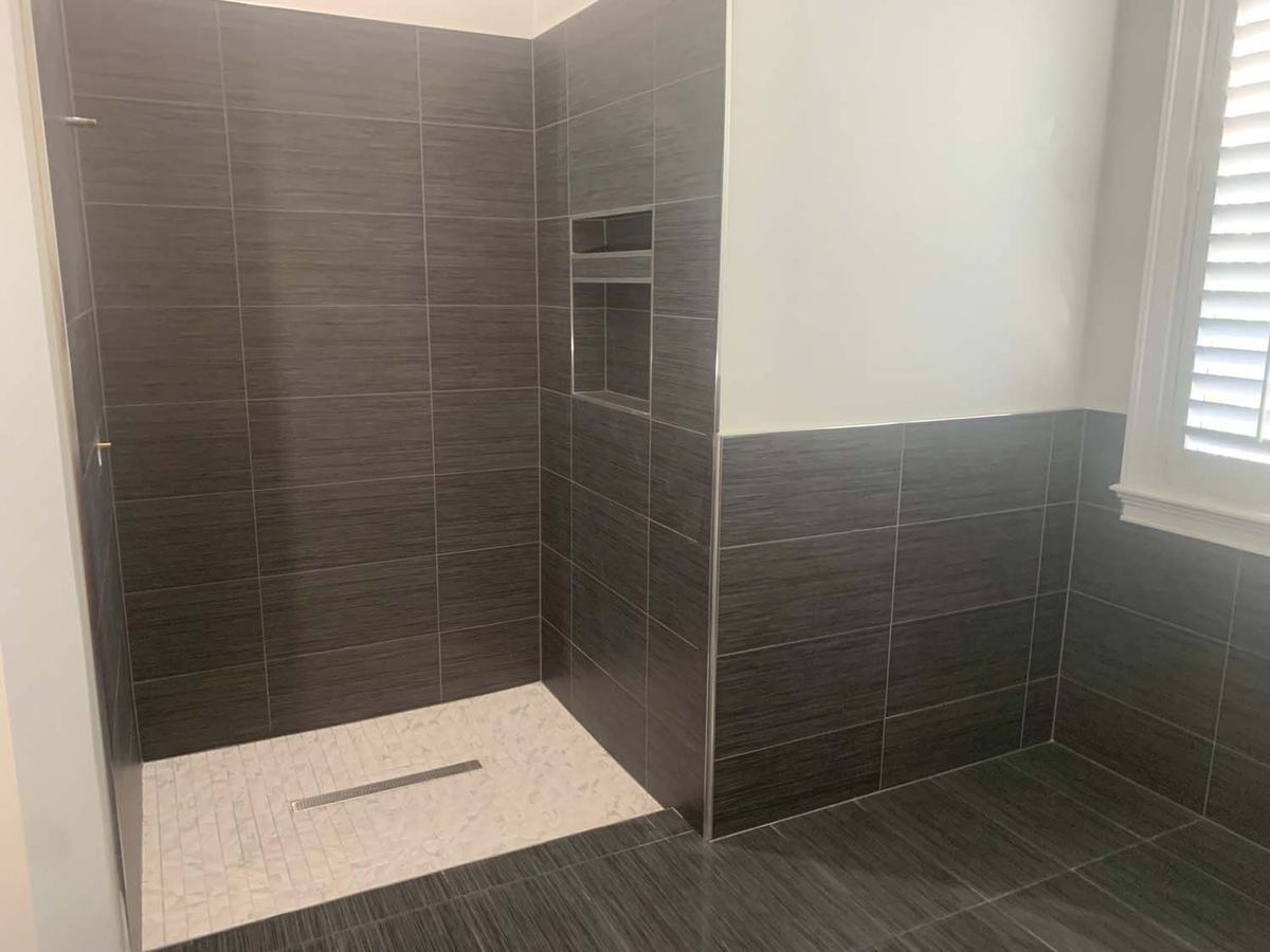 Dark plank tile shower with a linear drain and a niche