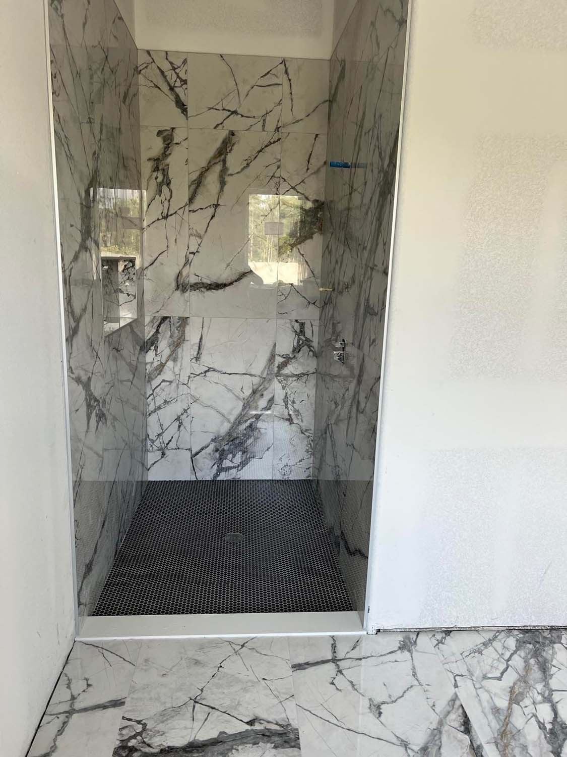 Black-veined marble-look shower with a dark floor