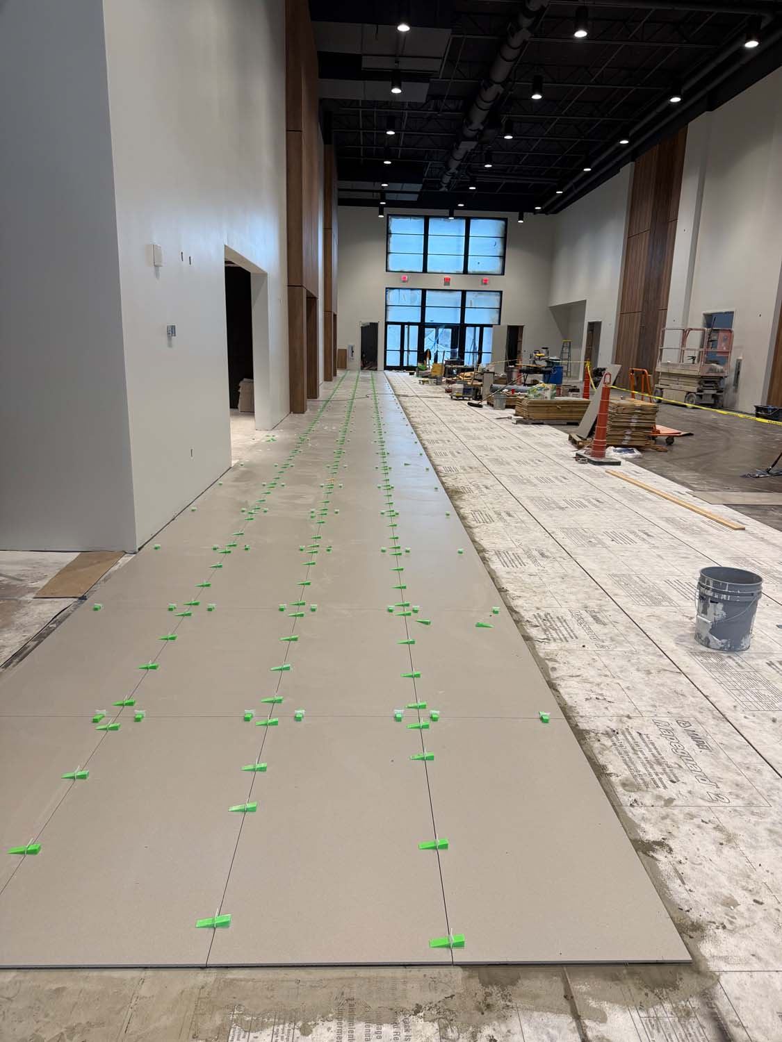 Large-format tile being set with leveling clips in a commercial corridor