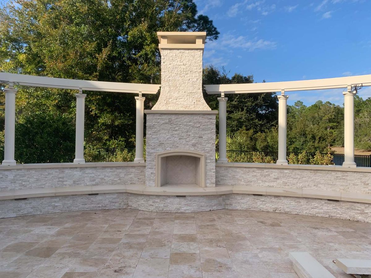 Travertine terrace with a stone fireplace and columns