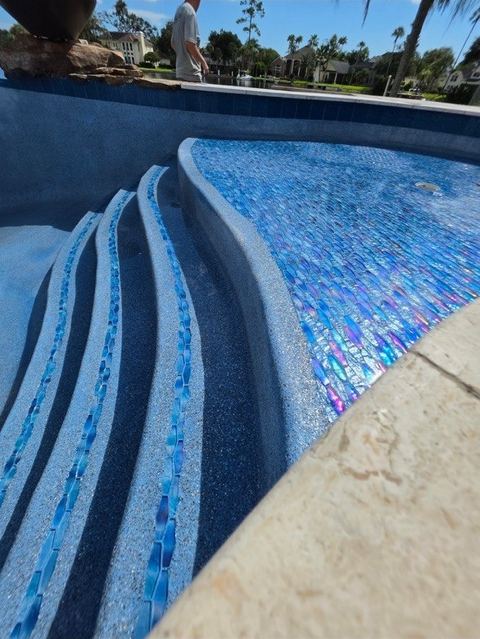 Pool steps and sun shelf with iridescent glass tile inlays, each piece laid by hand